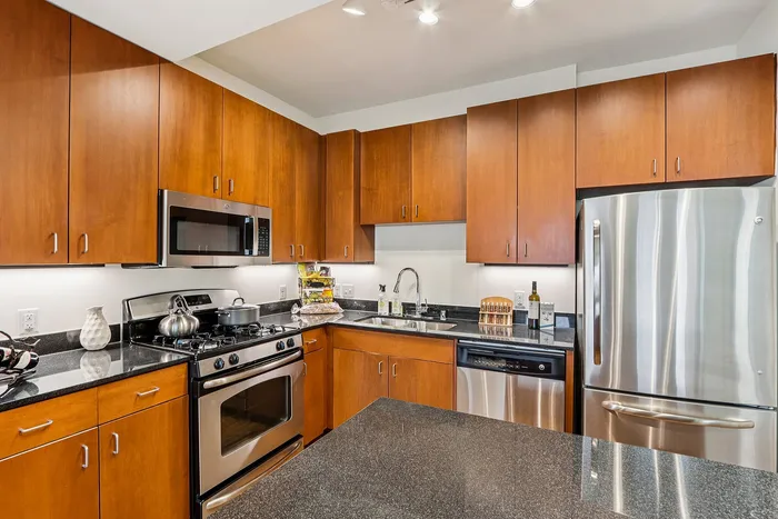 Modern kitchen with sleek stainless steel appliances, warm wooden cabinetry, and glossy countertops.