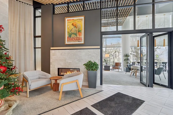 Elegant lobby with cozy seating by a modern fireplace, a festive Christmas tree, and expansive windows flooding the space with natural light.