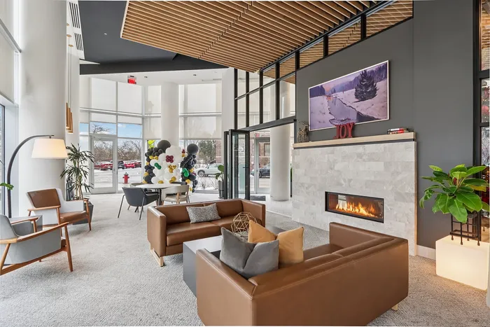 Elegant and inviting apartment lounge with modern furniture, cozy fireplace, and floor-to-ceiling windows offering natural light and vibrant decor.