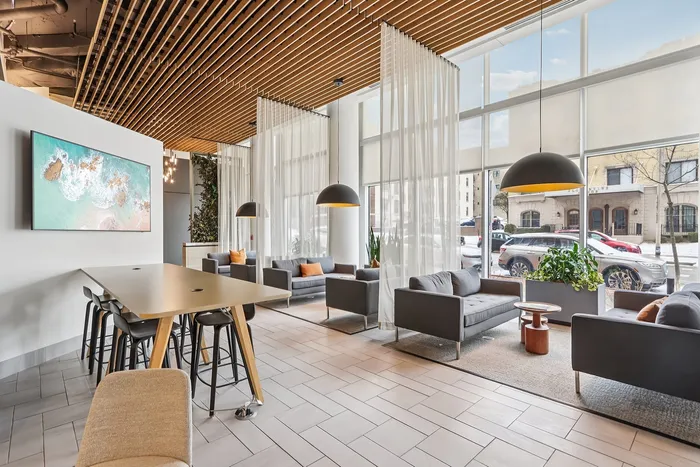 Chic and modern lounge area with stylish gray sofas, natural wood accents, and large windows allowing abundant natural light.