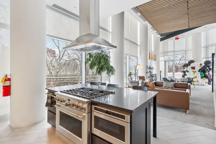 Luxurious open-concept apartment with modern kitchen, sleek island, and bright living area with floor-to-ceiling windows.