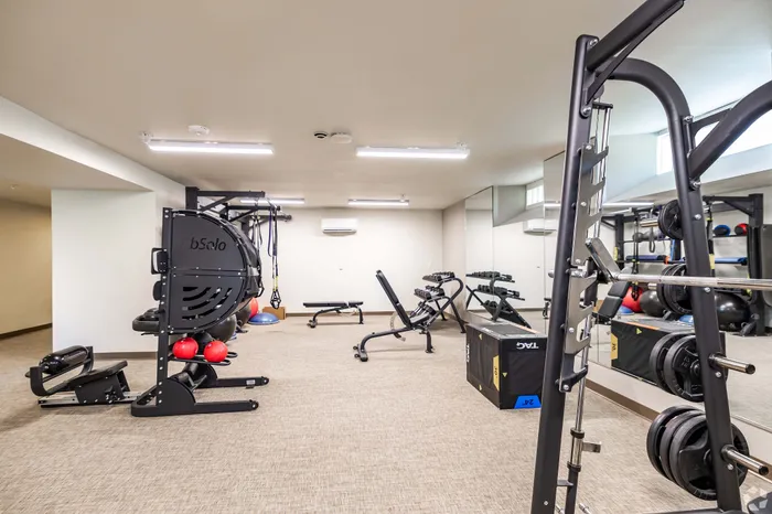 Modern, fully-equipped fitness center with weight racks, exercise machines, and ample space for workouts in a luxurious apartment complex.