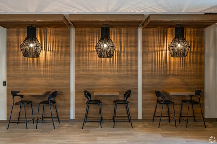 Chic dining area with modern pendant lights, sleek black chairs, and warm wooden accents, perfect for a contemporary apartment setting.