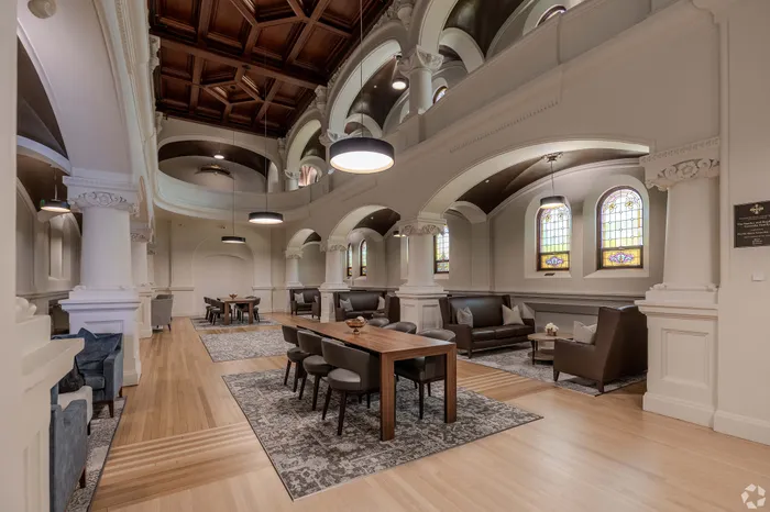 Elegant communal space with high ceilings, arched architecture, and cozy seating areas under beautiful stained-glass windows.