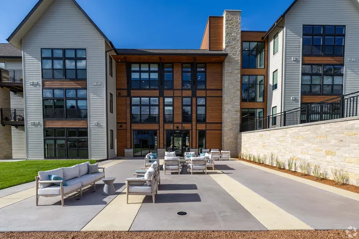 Modern apartment building with large windows and stylish outdoor seating area, perfect for relaxation and social gatherings.