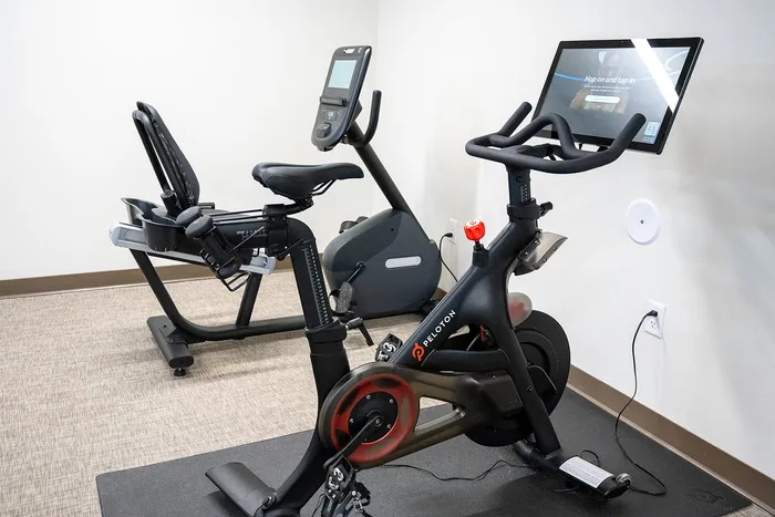 Modern fitness room featuring a high-tech Peloton bike and exercise equipment, perfect for home workouts.