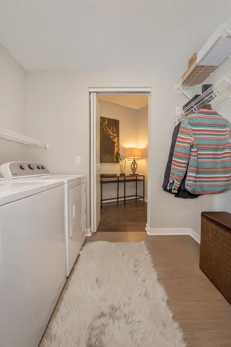 Chic laundry room featuring a modern washer and dryer, elegant decor, and ample shelving in a cozy apartment setting.