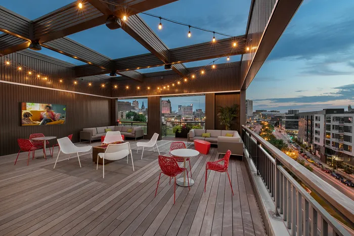 Chic rooftop terrace with cozy seating and city views, adorned with warm string lights and modern decor.