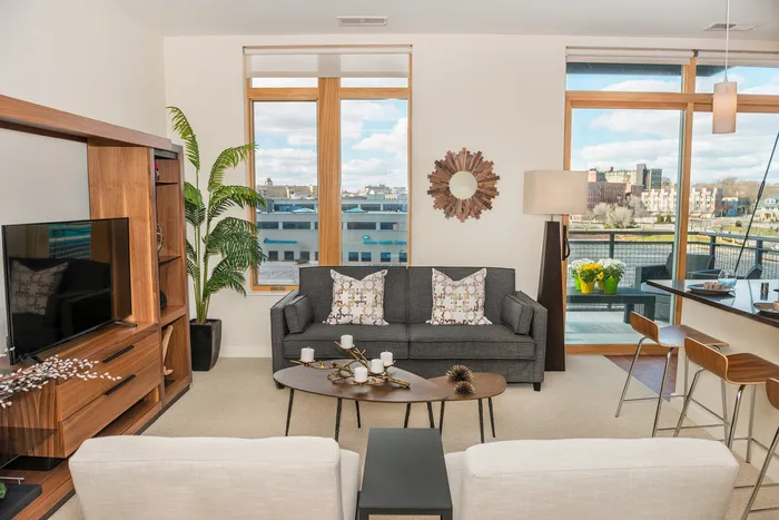 Bright and contemporary living room with large windows, chic decor, and a cozy seating area overlooking a scenic cityscape.