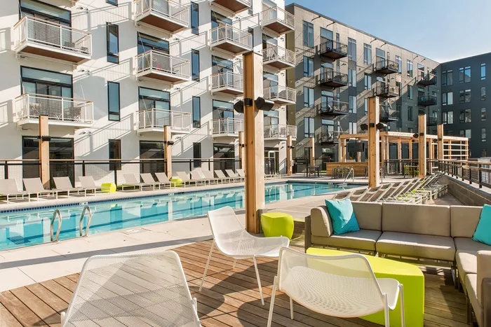Modern apartment complex showcasing a luxurious pool surrounded by stylish loungers and chic outdoor seating, perfect for relaxing and socializing.