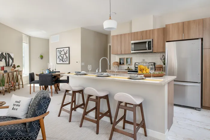 Contemporary open-concept kitchen with sleek wooden cabinetry, stainless steel appliances, and a chic dining area, perfect for stylish living and entertaining.