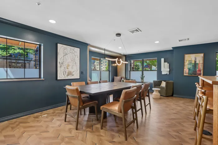 Elegant dining area with a modern dark table, stylish leather chairs, and chic contemporary art on deep blue walls.
