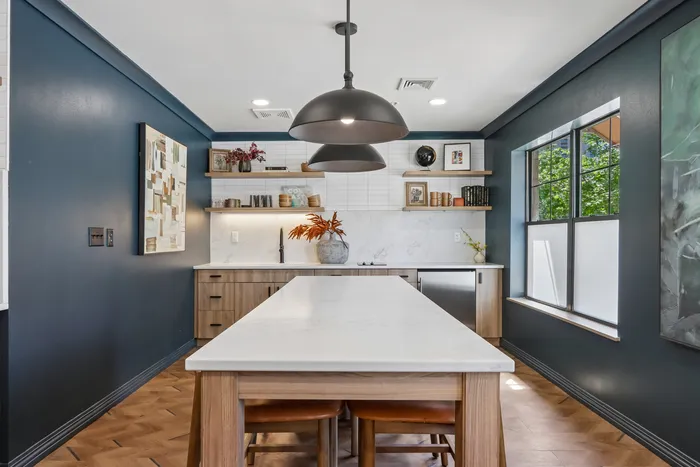 Modern kitchen with sleek pendant lights, elegant wooden cabinetry, and a chic marble island, offering a perfect blend of style and functionality.