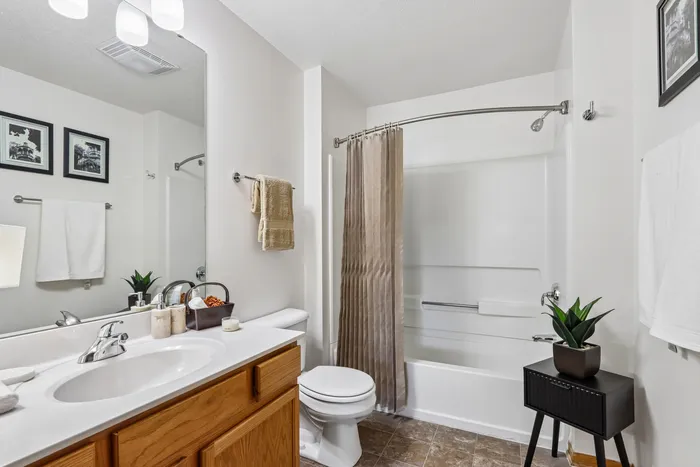 Modern bathroom featuring elegant lighting, smooth countertop with sink, stylish shower, and chic decor accents.