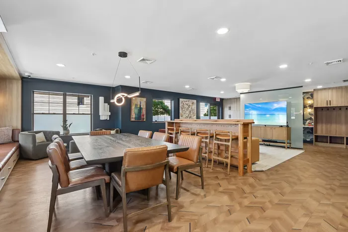 Modern open-concept living space featuring elegant dining area with leather chairs, cozy lounge with plush seating, and stylish wooden flooring.