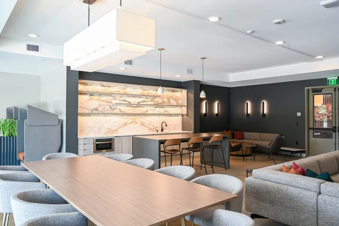Elegant and modern open-concept clubroom with a chic kitchen, stylish dining area, and cozy seating, perfect for entertaining.