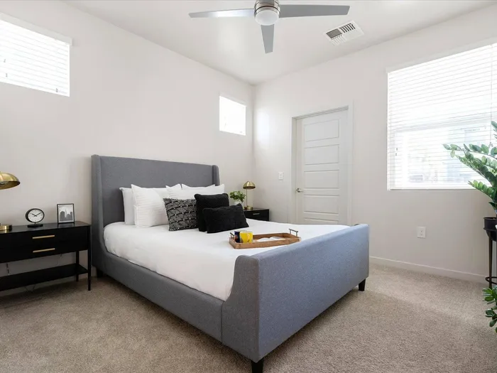 Apartments in Glendale, AZ, for Rent - Acero at the Stadium - Bedroom with a White and Gray Bed, Plush Carpeting, a Bedside Tables with Drawers, and Window with White Blinds.