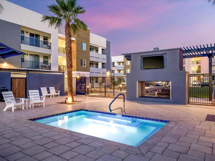 Two-Bedroom Apartments in Glendale, AZ - Acero at the Stadium - Fenced-In Outdoor Square-Shaped Hot Tub Surrounded by Concrete Tiles and White Lounge Seating.