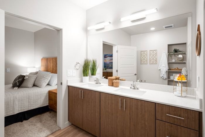 2-Bedroom Apartments in Queen Creek, AZ - Acero Harvest Station - Bathroom with Built-In Shelves, a Double Sink Vanity, and a Large Mirror