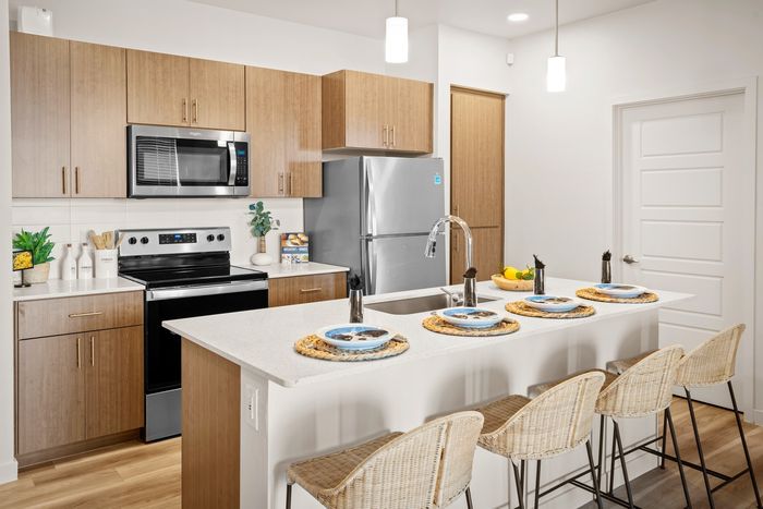 Luxury Apartments in Mesa, AZ - Acero Hawes Crossing - Kitchen with Quartz Countertops, Stainless Steel Appliances, Kitchen Island, and Vinyl Plank Flooring.