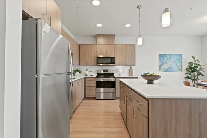 Vancouver, WA Dog-Friendly Apartments - Acero Jensen Park - MOdern Kitchen with Wood-Style Cabinetry, Stainless Steel Appliances, White Countertops, and Large Cooking Island
