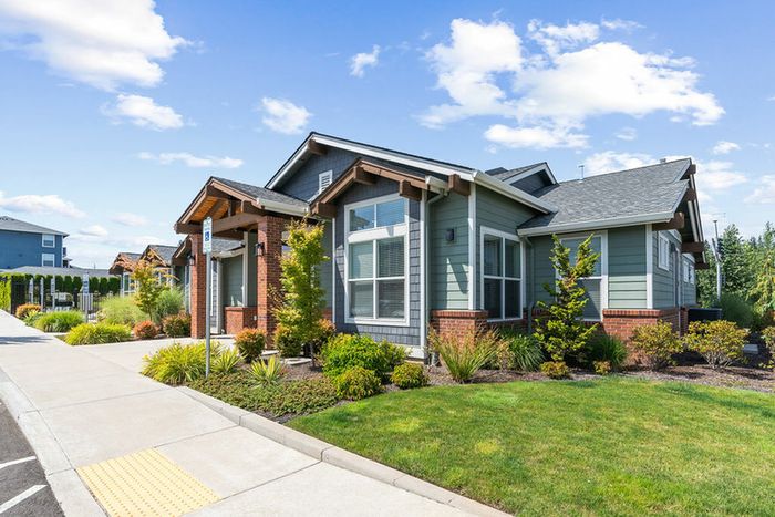Pet-Friendly Apartments in Vancouver, WA - Acero Jensen Park - A Front Exterior with Landscaped Greenery, Sidewalks, Large Windows, and Modern Architectural Details.