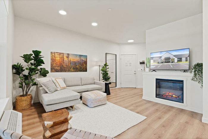 Vancouver, WA apartments for Rent - Bennington on First - Living Room - Couch - Fireplace - Wood-Style Flooring - Rug - Plant