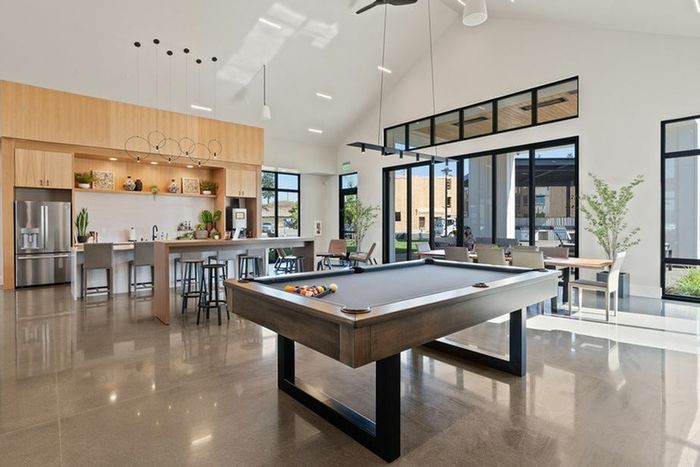 2-Bedroom Apartments in Camas, WA - Bennington on First - Bright Community Lounge With Pool Table, Bar Seating, Stainless Steel Appliances, High Ceilings, And Large Windows Overlooking Patio.