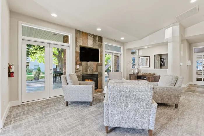 Elegant living room featuring contemporary seating, a cozy fireplace, and large windows opening to a lush garden view.
