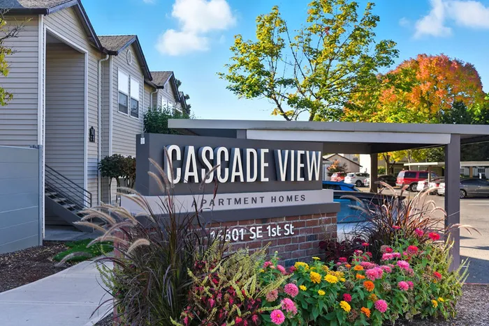Charming Cascade View Apartments sign amidst vibrant landscaping, showcasing welcoming exteriors under a clear blue sky.