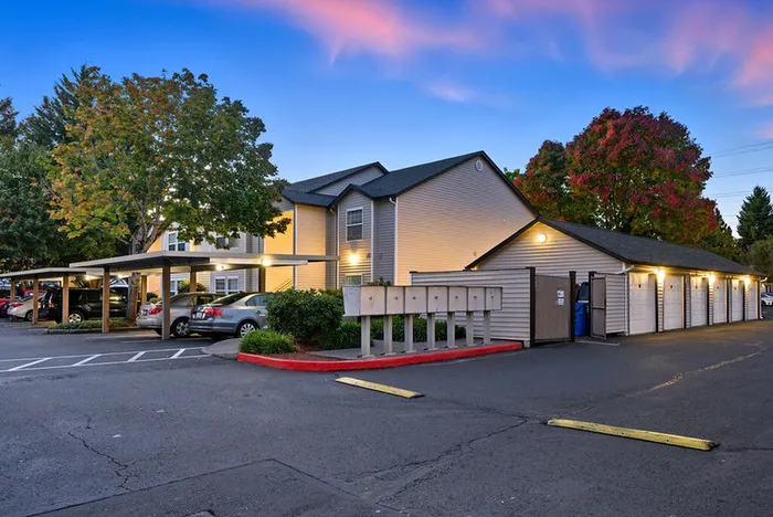 Charming apartment complex with well-maintained landscaping, ample parking, and vibrant sunset skies.