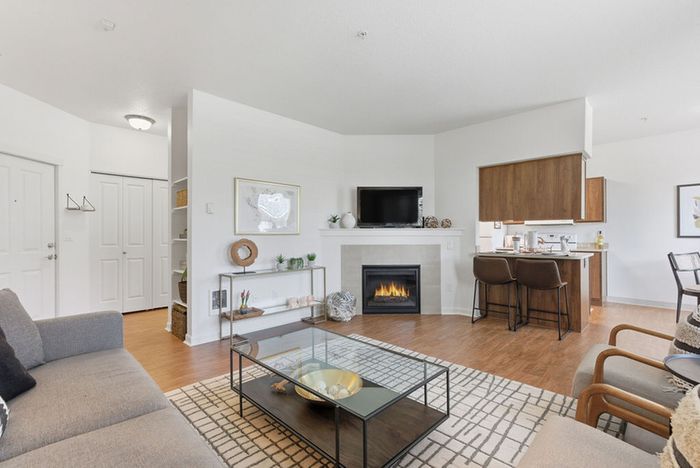 Inviting living room with modern fireplace, cozy seating area, and open layout leading to a stylish kitchen with a breakfast bar.