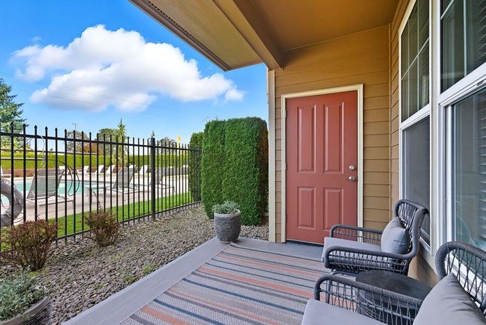 Charming outdoor patio with cozy seating overlooking a pristine swimming pool and lush greenery, perfect for relaxation.