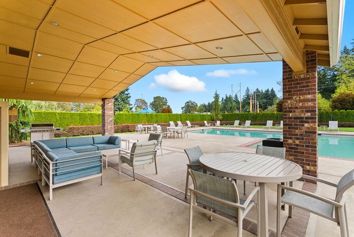 Charming outdoor patio with inviting seating area and tables, overlooking a pristine swimming pool, perfect for relaxation and entertaining guests.