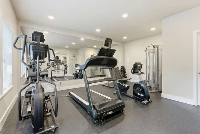 Elegant in-house gym with state-of-the-art equipment including treadmill, elliptical, and stationary bike, offering a bright and energizing workout space.