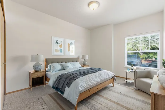 Bright and cozy bedroom featuring a comfortable bed, elegant decor, and large window with scenic views.