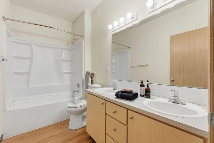 Bright and inviting bathroom with a dual-sink vanity, large mirror, and a spacious tub, ideal for relaxation.