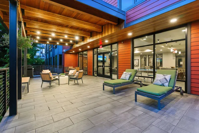 Inviting apartment patio with modern lounge chairs, cozy seating area, and stylish wooden ceiling, perfect for relaxation and entertaining.