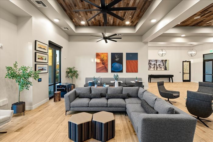 Modern lounge area with contemporary decor, featuring plush gray seating, vibrant artwork, and stylish wood-paneled ceilings.