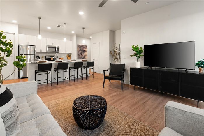 Modern open-concept living room with sleek kitchen and breakfast bar, featuring elegant decor and ample natural light.