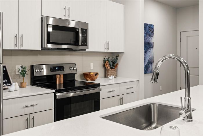 Chic and modern kitchen with sleek stainless steel appliances and elegant white cabinetry, offering a sophisticated cooking space.