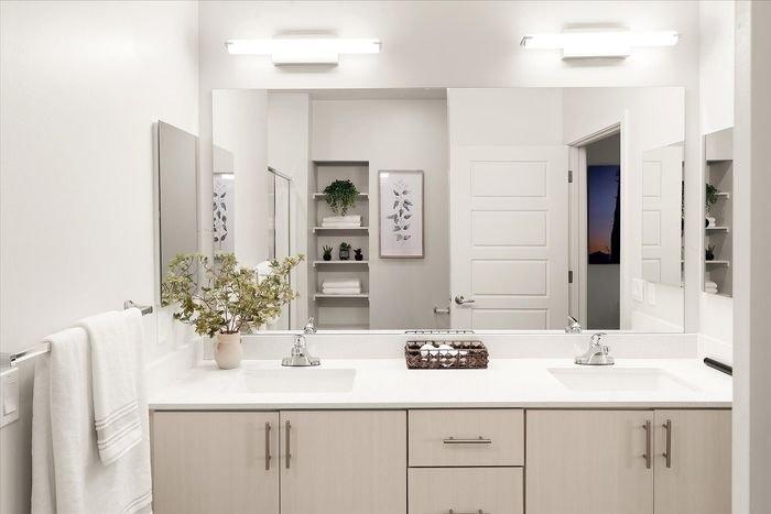 Elegant bathroom with double sinks, modern fixtures, and ambient lighting, featuring minimalist decor and a touch of greenery.