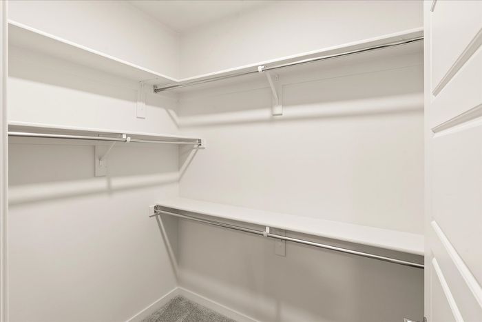 Spacious walk-in closet with ample shelving and hanging space, ideal for organized storage solutions.