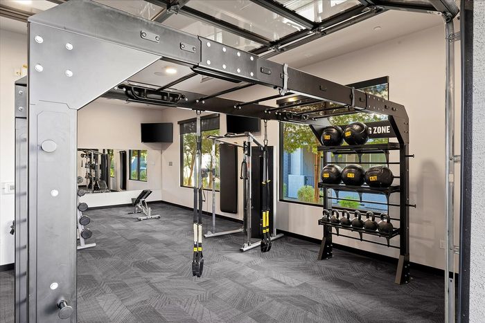 Modern gym with state-of-the-art equipment, featuring TRX straps, kettlebells, and medicine balls in a bright, spacious room.