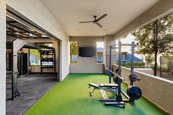 Modern outdoor gym area featuring state-of-the-art fitness equipment and lush greenery, perfect for an invigorating workout experience.