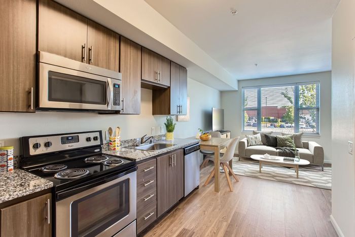 Inviting open-concept kitchen and living area with modern appliances, elegant wooden cabinets, a cozy dining setup, and a sunlit seating space.