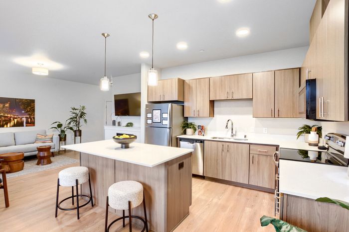 Pet-friendly apartments in Vancouver, WA Modern open-concept kitchen and living area with sleek wooden cabinets, stainless steel appliances, and stylish pendant lighting.