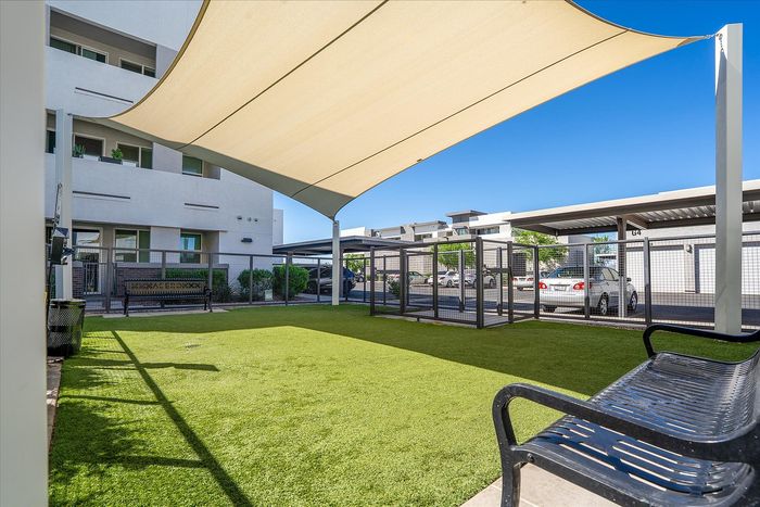 Inviting community dog park with shade sail and seating, offering a relaxing green space at the apartment complex.