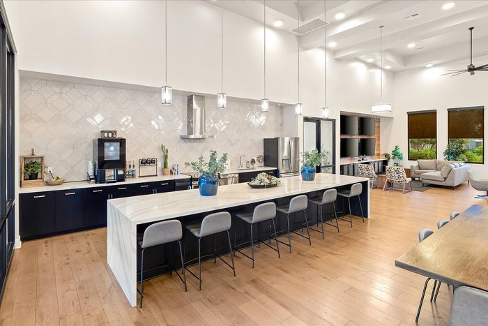 Spacious modern kitchen and living area with sleek countertops, elegant lighting, and cozy seating, perfect for entertaining.