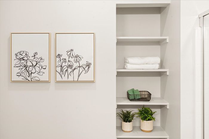 Chic bathroom shelf with minimalist floral art, neatly folded towels, and vibrant green plants for a refreshing ambiance.